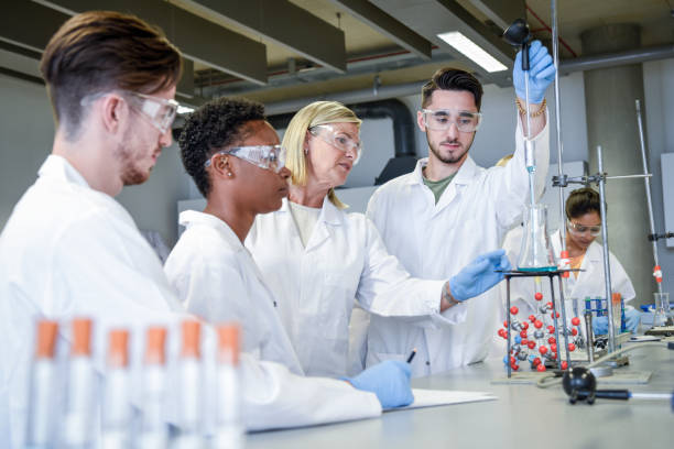 science teacher teaching young chemistry students in laboratory - professor scientist chemistry teacher imagens e fotografias de stock