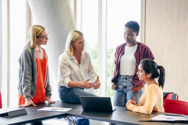 istock Mature female teacher explaining to three female college students 827810758