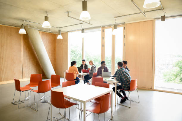 istock College students sitting at tables and chairs in modern common room 827810802