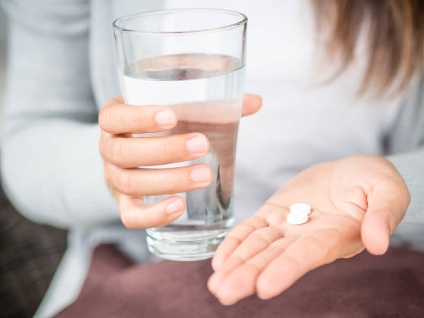 Closeup woman hand with pills medicine tablets and glass of water for headache treatment. Healthcare, medical supplements concept Closeup woman hand with pills medicine tablets and glass of water for headache treatment. Healthcare, medical supplements concept aspirin photos stock pictures, royalty-free photos & images