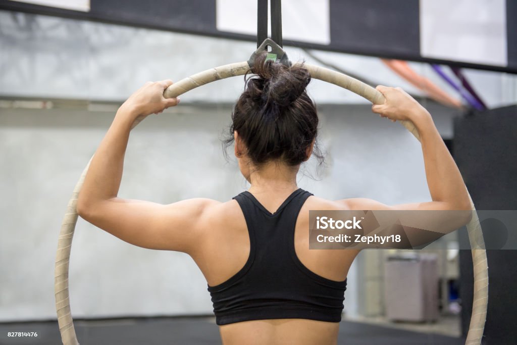 young asian acrobatic woman doing her gymnastics performance on aerial hoop young asian acrobatic woman doing her gymnastics performance on aerial hoop or aerial ring Acrobat Stock Photo