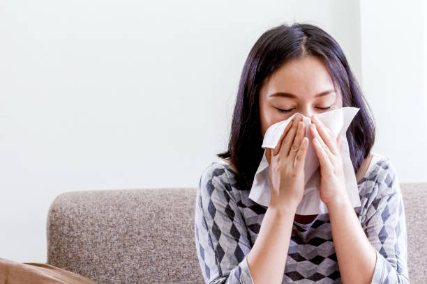 istock Sick woman blowing her nose with tissues 827820912
