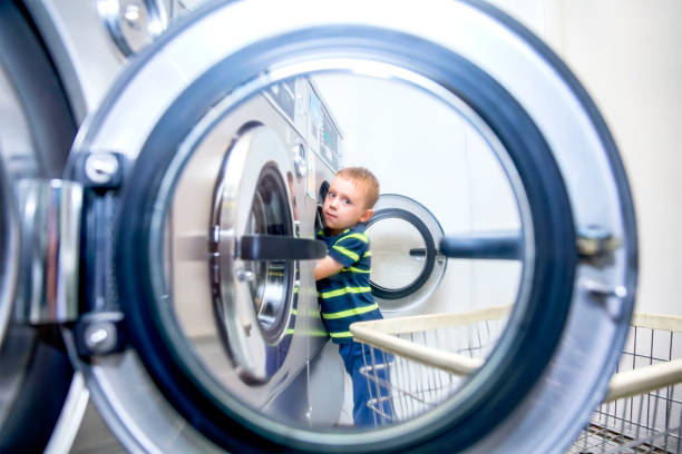 istock Boy puts clothes in a washing machine in a public laundry 827824884