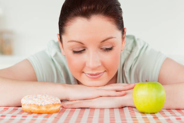 istock Good looking woman posing with a donut and a green apple 827829080