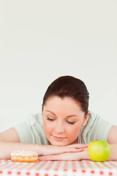 istock Cute woman posing with a donut and a green apple 827829106