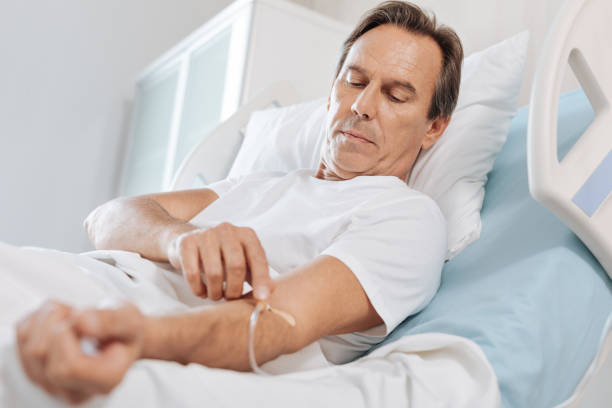 istock Nice serious man touching the IV catheter 827829876