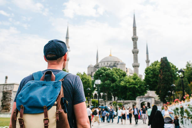 un uomo con un berretto da baseball con uno zaino accanto alla moschea blu è uno spettacolo famoso a istanbul. viaggi, turismo, visite turistiche. - baseball cap cap men baseball foto e immagini stock