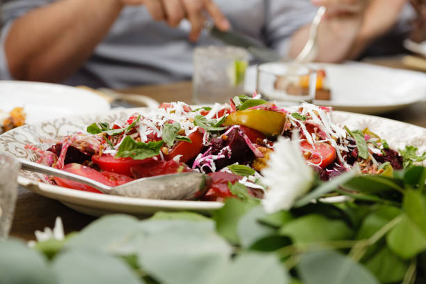 Beet salad with tomatoes, plums, ricotta and almond in a white serving dish