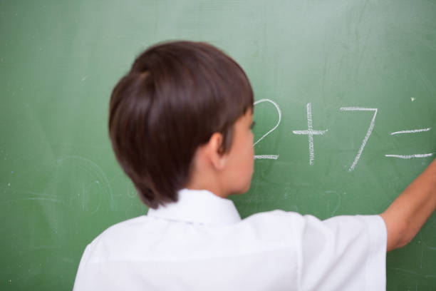 istock Little schoolboy writing an addition 827840688