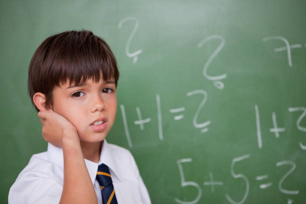 istock Confused schoolboy thinking while scratching the back of his head 827841462
