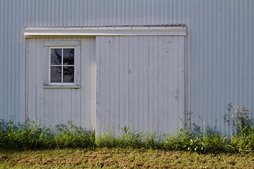 Interesting front view of an old sliding barn door with a small four-pane window.