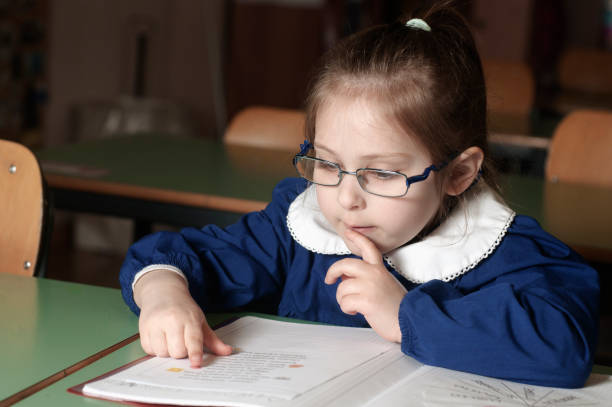 istock Italian elementary school girl first-grader reading on school 827848314