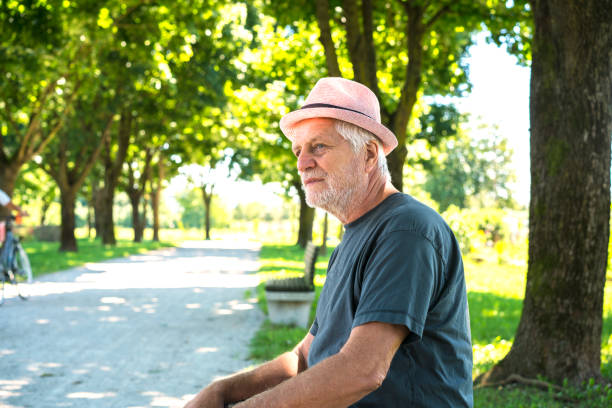istock Side view of Senior sitting on bench in Park 827855410