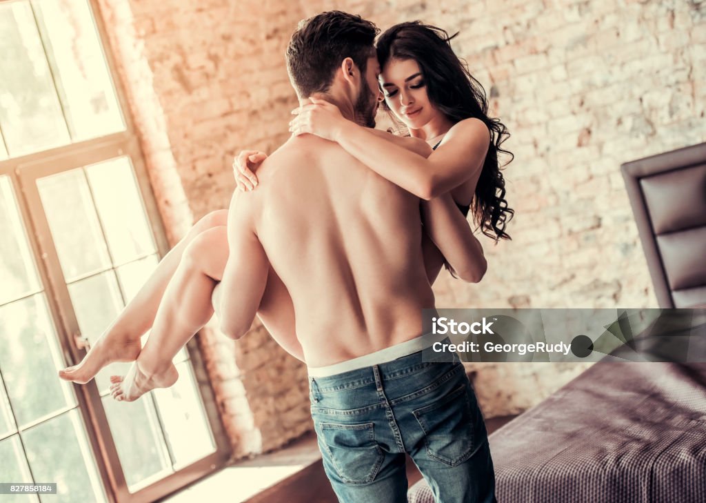 Sexy young couple Sexy young couple at home. Handsome topless man is holding smiling woman in his arms Sensuality Stock Photo