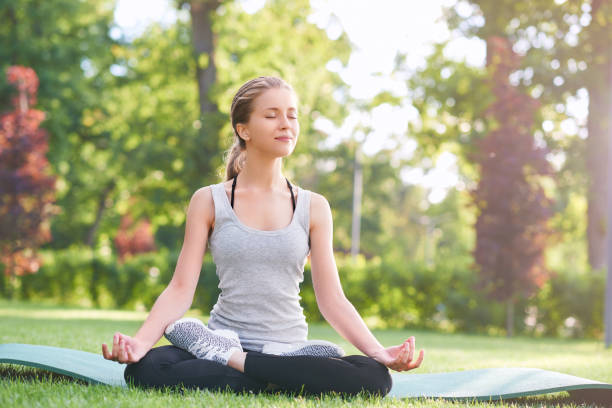 istock Young woman practicing yoga outdoors at the park 827863412