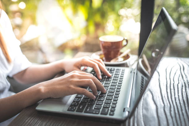 istock young woman keyboarding on laptop computer sitting in cafe 827866956