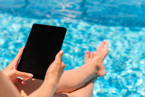 istock Woman holding digital tablet by the pool 827871360