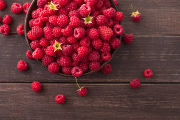 istock Red fresh raspberries on brown rustic wood background 827871550