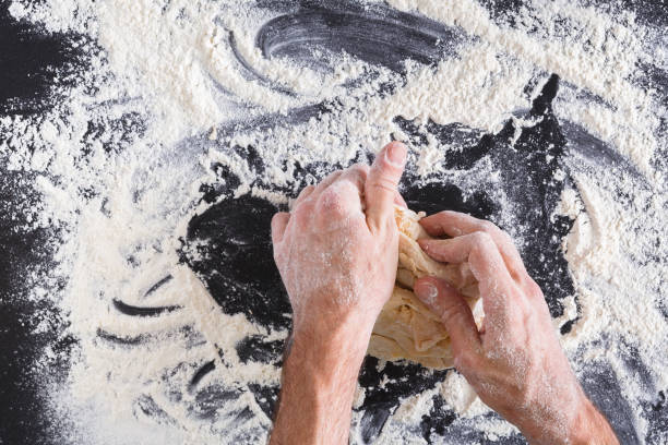 istock Hands top view knead dough on black background 827878816
