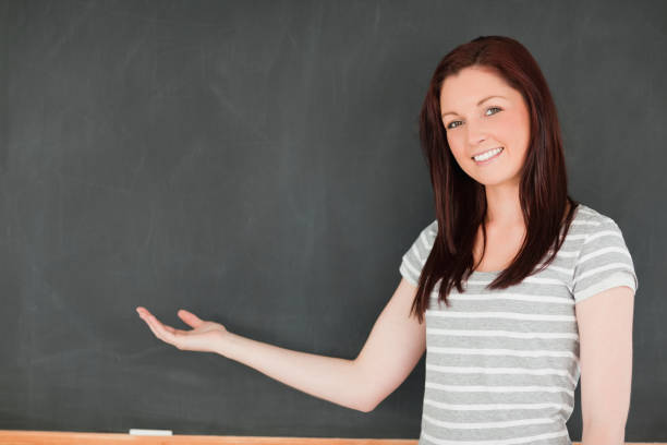 istock Smiling woman against blackboard with a copy space 827881732