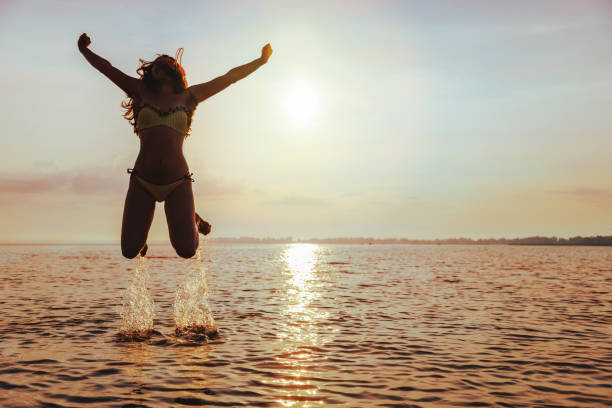 istock Young Woman Jumps on Beach at sunset 827884206