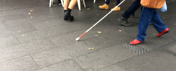 Visually impaired person walks in the street Unrecognisable Visually impaired person walks in the street with a long white cane stick blind persons cane stock pictures, royalty-free photos & images