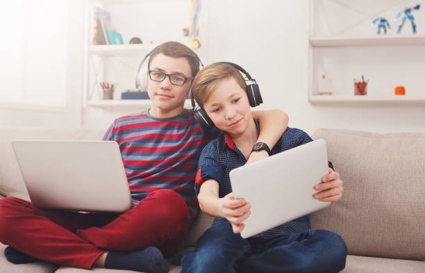 istock Two teenage boys using tablet on couch at home 827888112