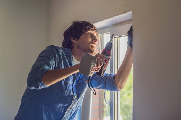 istock Man in a blue shirt does window installation 827891424