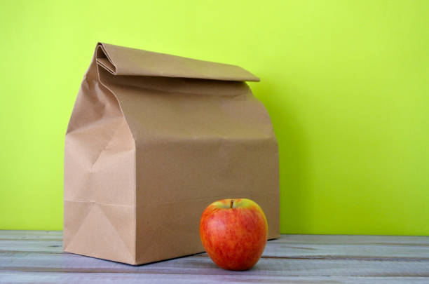 Lunch packed in a brown paper bag with red apple. Healthy food concept. Copy space