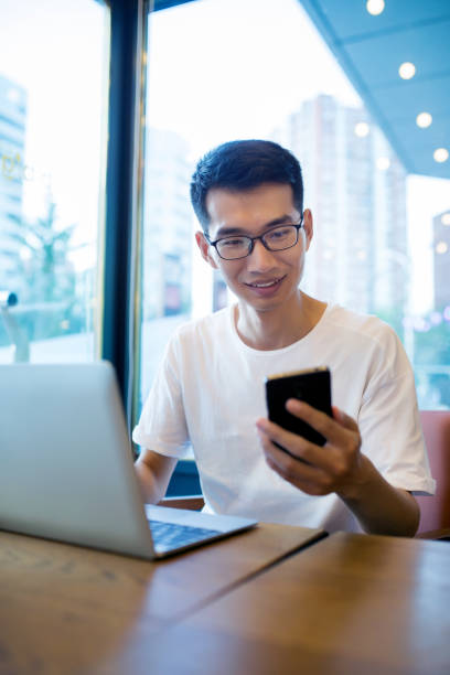 istock Man using laptop and phone at cafe 827897072