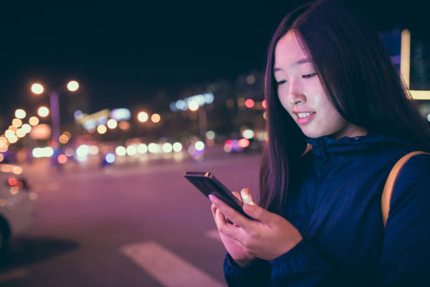 istock Woman using her mobile phone at night street 827901168