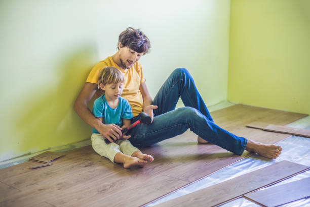 istock Father and son installing new wooden laminate flooring. infrared floor heating system under laminate floor 827901510