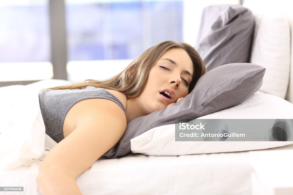 Tired woman resting on a bed at home Tired single woman resting on the bed of an hotel room or home Sleeping Stock Photo