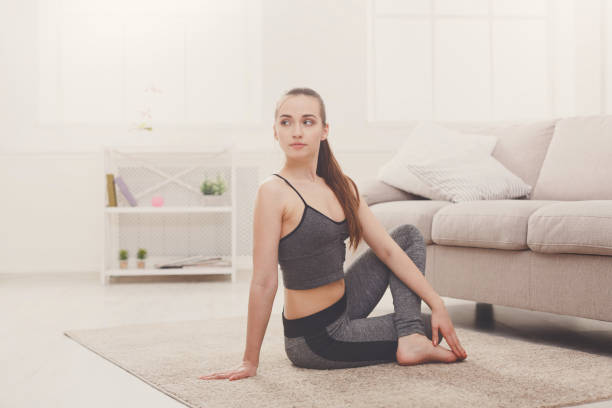 istock Yoga at home. Woman stretching seated spinal twist pose 827904672