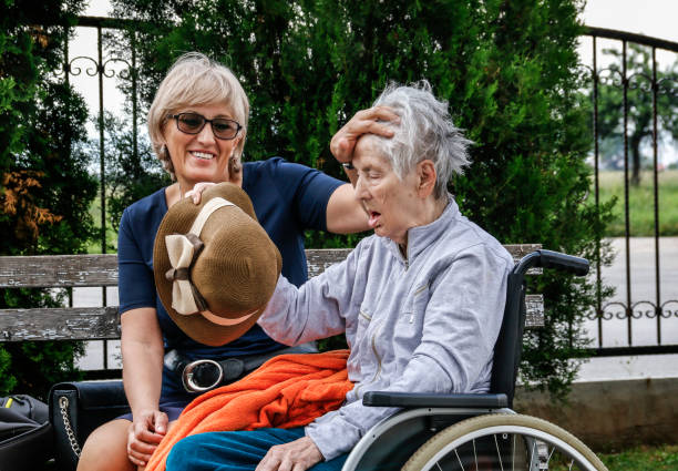 Mother ans daughter outdoors. Senior woman in wheelchair.