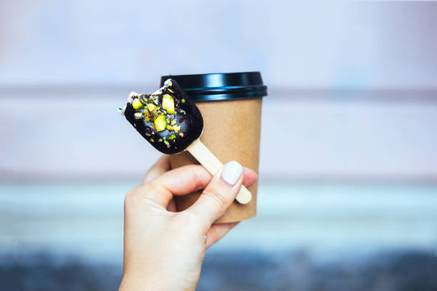 istock Woman's hand holding chocolate popsicle 827921088