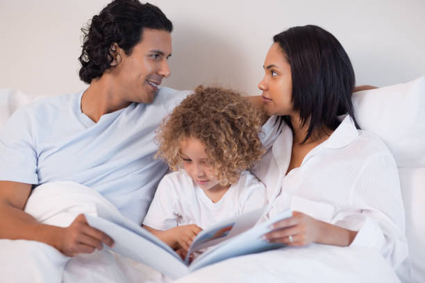 istock Family sitting on the bed reading a book 827928620