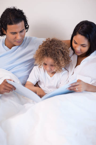 istock Family sitting on the bed reading a story 827928656