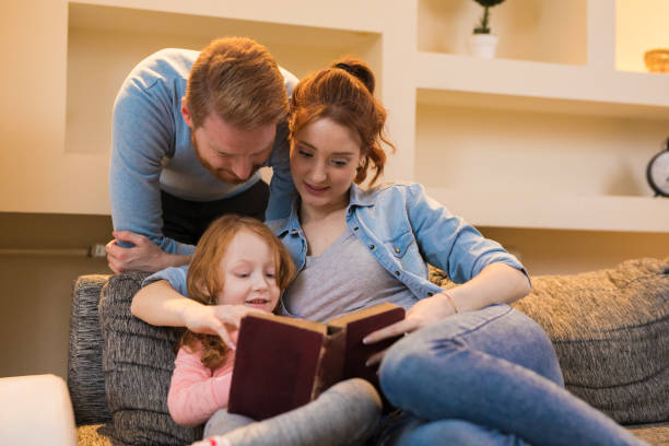 istock Young parents reading interesting book to daughter at home 827933070