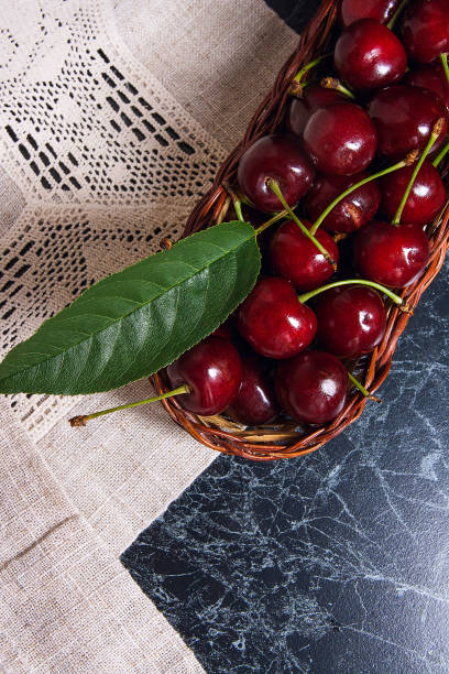 Cherry and big green leaf in yellow wooden basket