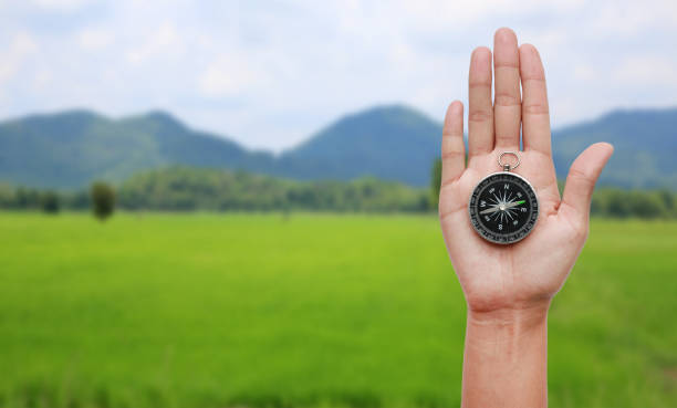 istock Compass in hand against nature landscape background. 827935516
