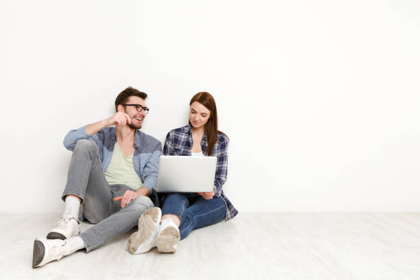 istock Smiling couple web-surfing on laptop, studio shot 827947418