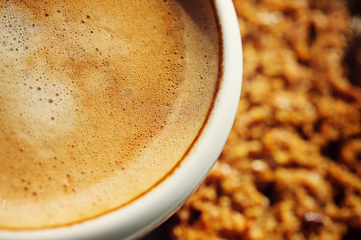 Coffee cup with a whole grain rusk beskuit on the saucer with a tall shadow to the left Stellenbosch Cape Town South Africa