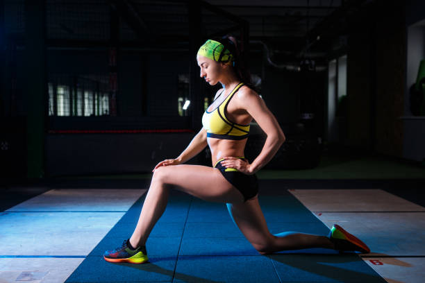 istock beautiful, strong, slender, in good physical shape in the gym doing exercises. Dressed in short shorts and tank top green, on the head bandage. 827951418