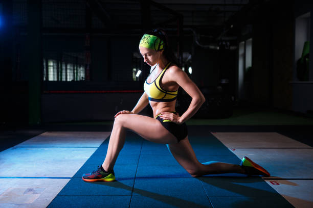 istock beautiful, strong, slender, in good physical shape in the gym doing exercises. Dressed in short shorts and tank top green, on the head bandage. 827951438