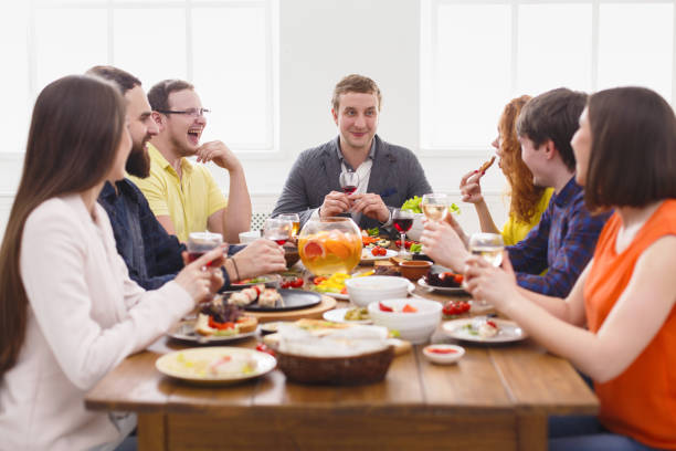 istock Group of happy people at festive table dinner party 827954138