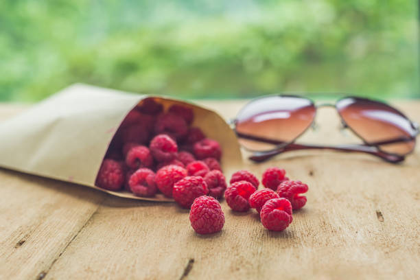 Summer holiday, vacation, relaxation concept. Raspberries, straw hat, on wooden background. Free text copy space. Summer vibes concept