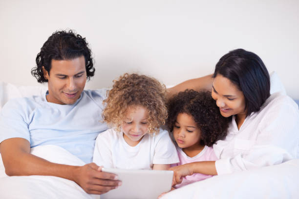 istock Family sitting on the bed surfing the web 827959136