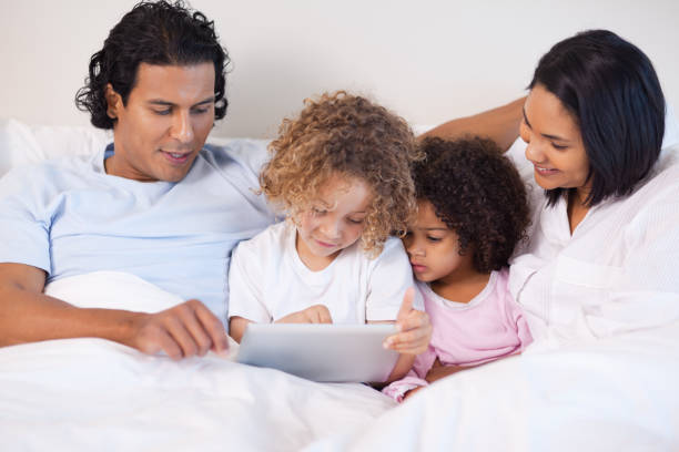 istock Family sitting on the bed using tablet 827959210
