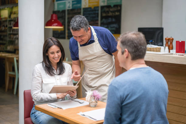 istock Waiter explaining the menu to a couple at a restaurant 827959316